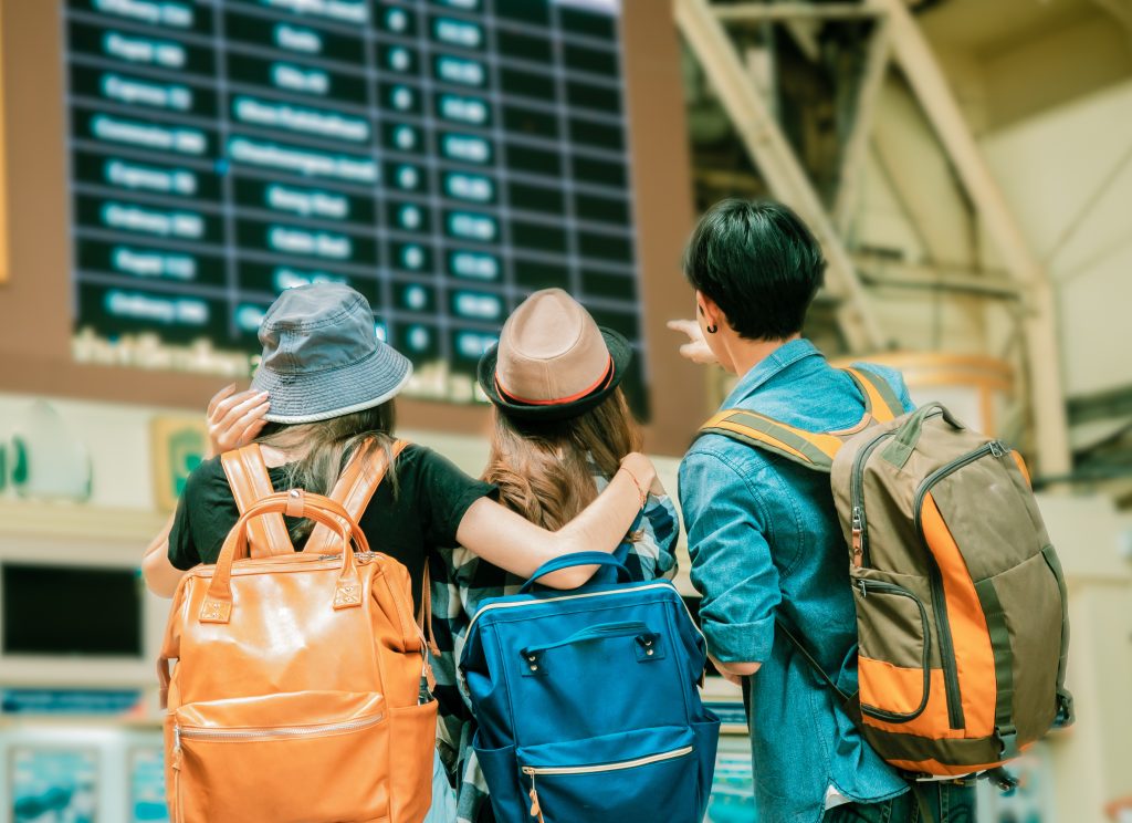 Three travellers looking at time board for traveling.